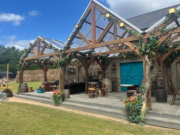 A wooden building structure with a blue dor in the middle, as well as small tables