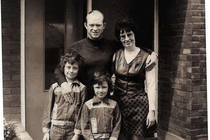 Black and white family portrait of John and Jean Kemp and their children, actor Ross Kemp and his brother Darren, standing in a doorway.