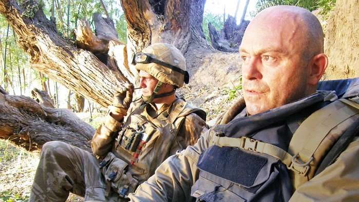 Ross Kemp wearing an armoured vest in a dugout in Helmand, Afghanistan with a member of the Armed Services