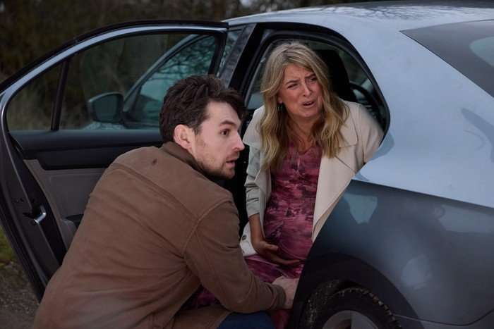 Mack sits beside Charity, who is sat in a car and in labour, in a scene from Emmerdale