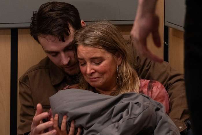 Charity and Mack, sat on the floor of a lift, holding baby Leyla in Emmerdale