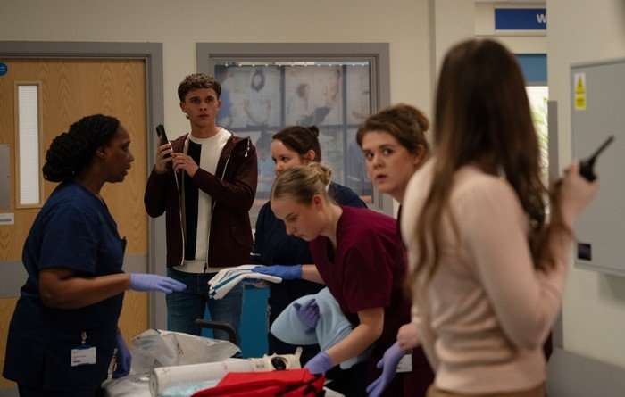 Jacob and Sarah watch on as Charity is rushed off in a hospital bed in a scene from Emmerdale