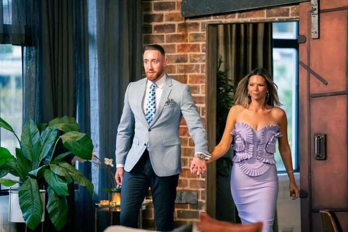 Bec and Danny walking hand-in-hand into the dinner party in glam attire.