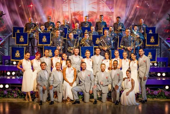 The Strictly Come Dancing professionals in two rows, some knelt down and others stood up, smiling ahead as they pose.