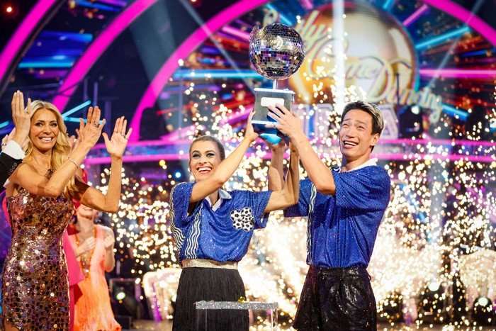 Karen Carney and Carlos Gu stood next to each other both raising a trophy in the air as their celebrate their Strictly win.