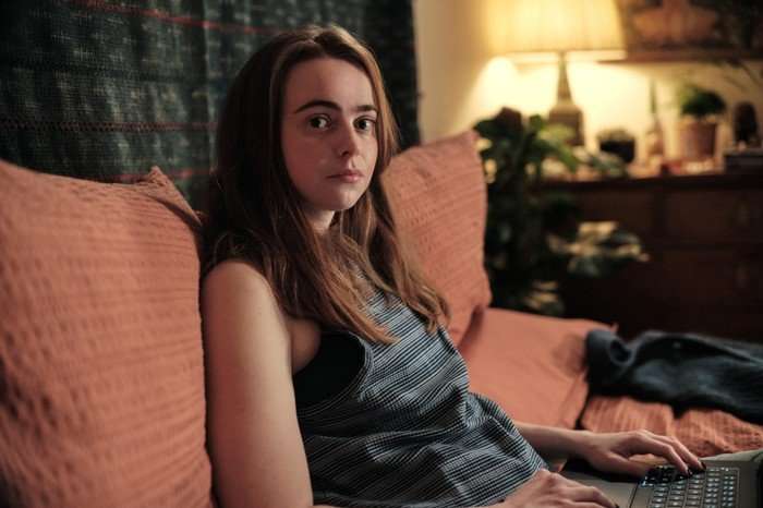 Daisy Waterstone as Abigail Carey in The Capture, sat on a sofa and looking at the camera.