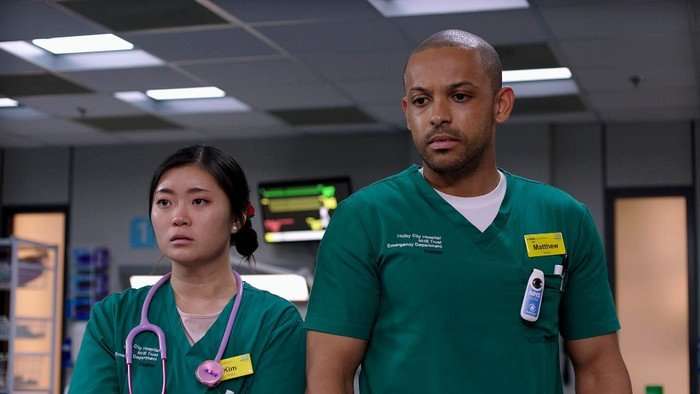Jasmine Bayes as Kim and Aron Julius as Matty stood next to each other in green scrubs.