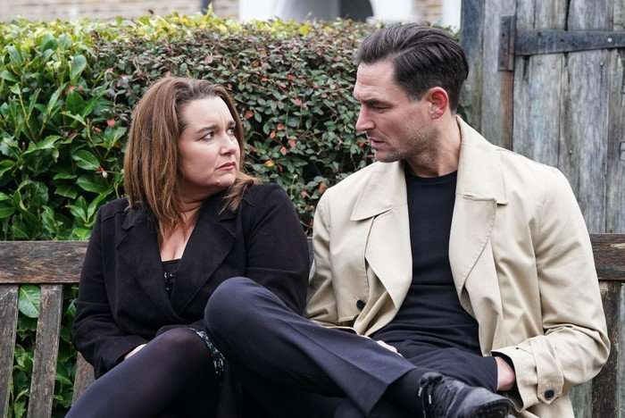 Vicki and Zack stare into one another's eyes with worried expressions on their face, sat in the Square gardens in EastEnders