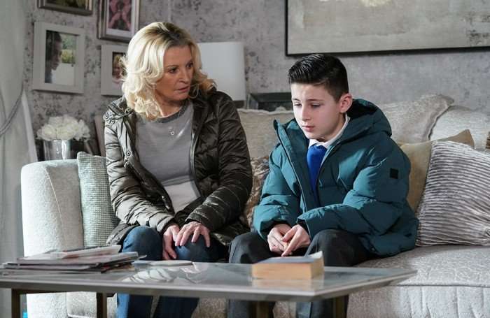Louie and Kathy sat on Vicki's sofa in a scene from EastEnders