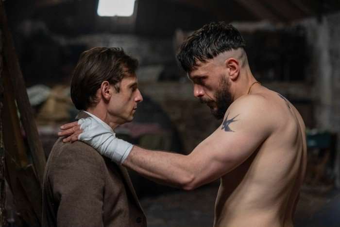 Jamie Bell as Niall and Richard Gadd as Ruben in Half Man. Ruben is shirtless and has a bandage around his hand. He is putting it on Bell's shoulder.