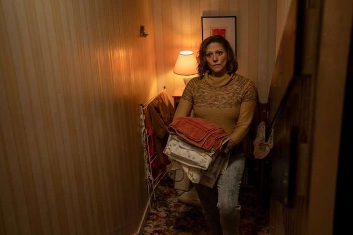 Neve McIntosh as Lori in Half Man, holding a pile of laundry and stood in a house.