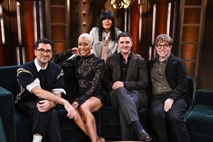 Dan Levy, Cush Jumbo, Phil Dunster and Josh Widdicombe all sat down on a dark green sofa smiling ahead, while Claudia Winkleman stands behind them.