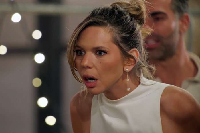 Bec on MAFS Australia wearing a white dress looking shocked at something in front of her.