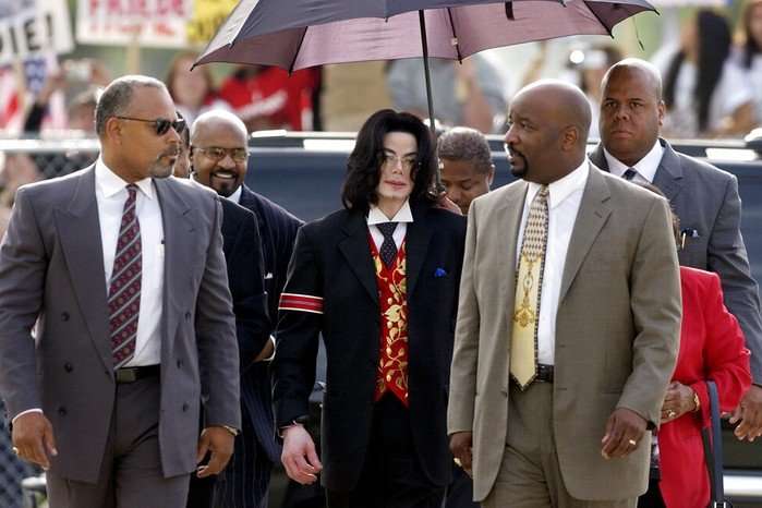 Michael Jackson walking alongside a group of men in suits