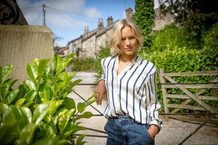 Georgia Jay poses as Steph Miligan in the Emmerdale village, leaning on a fence