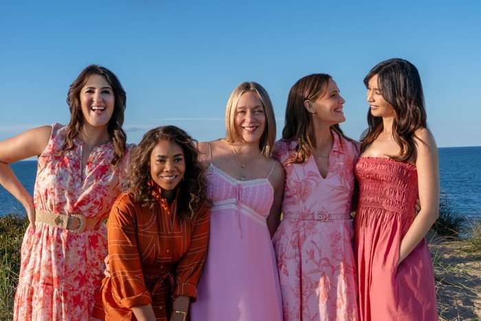 Five women standing on the beach.