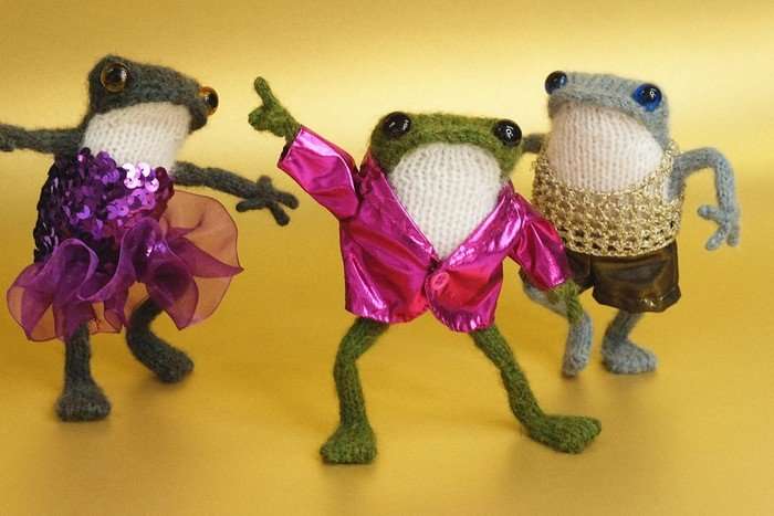 Three hand-knitted wool frogs dancing