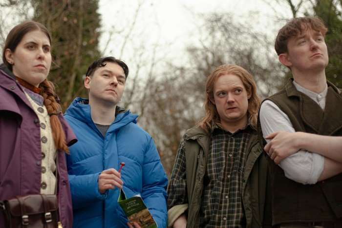 Four people standing in the woods.