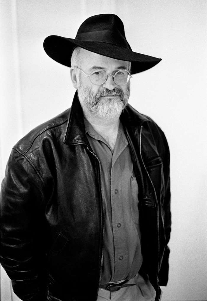 Terry Pratchett wearing a black leather jacket and large-rimmed hat.