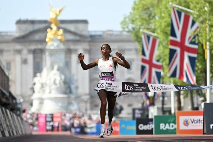 Tigst Assefa, in white race kit, crosses the finish line at the London Marathon 2025.