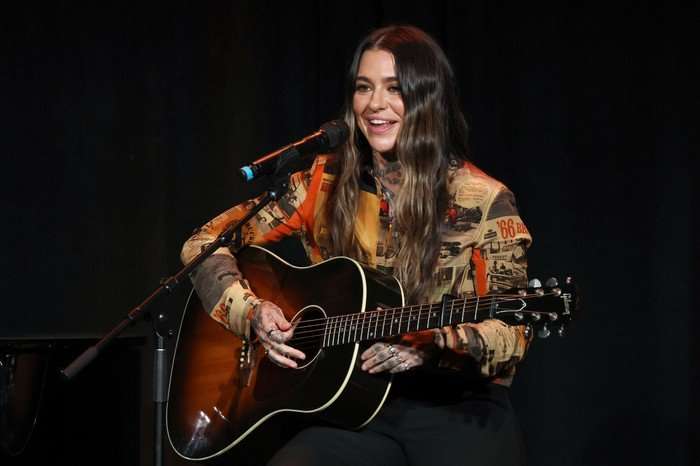 Morgan Wade, sat on stage with a guitar and a microphone.