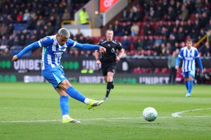 Brighton midfielder Diego Gomez, in white and blue football, shoots on the pitch at Turf Moor.