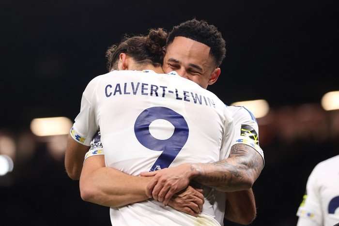 Leeds United footballers Noah Okafor and Dominic Calvert-Lewin, in white and blue kit, hug on the pitch at Old Trafford.