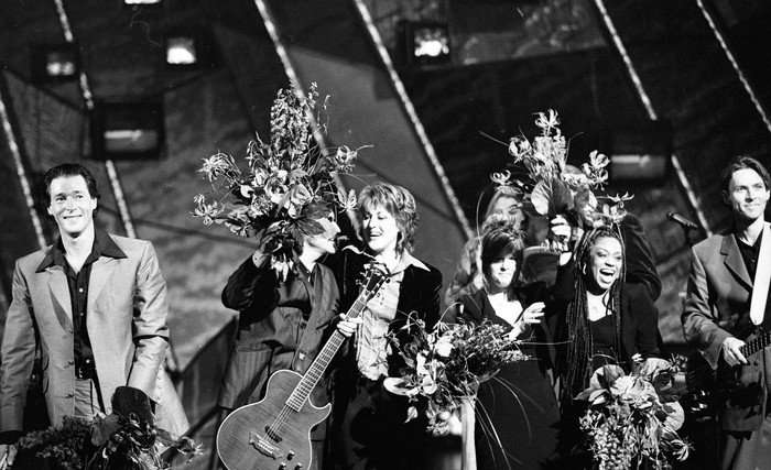 A group of people all stood around on stage, celebrating.