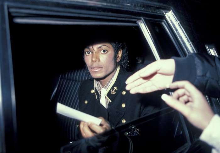 Michael Jackson sat in the backseat of a car, looking directly into a camera.
