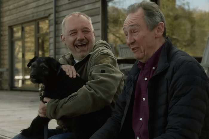 Bob Mortimer and Paul Whitehouse holding a dog and smiling.