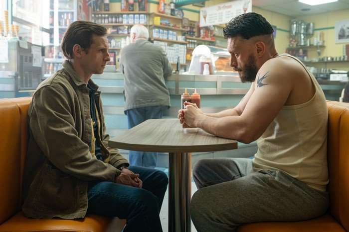 Richard Gadd in a sleeveless vest and joggers sits opposite Jamie Bell in a jacket and jeans during a serious caf&eacute; conversation in Half Man.