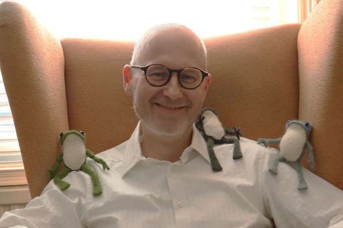 Holger Auffenberg with three knitted frogs on his shoulders.