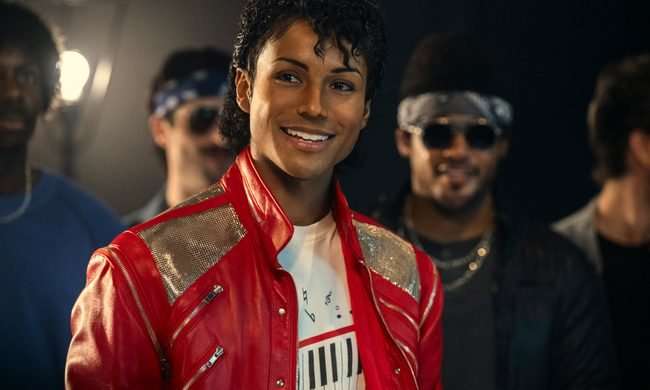 Jafaar Jackson smiling and wearing a red jacket as Michael Jackson in the 2026 Lionsgate film, Michael.