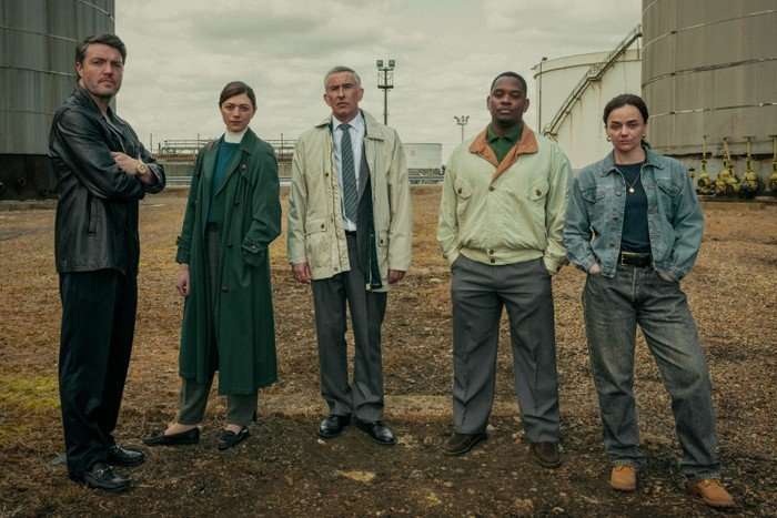 Tom Burke as Guy, Jasmine Blackborow as Erin, Steve Coogan as Don, Aml Ameen as Bailey and Hayley Squires as Kate in Legend, stood next to each other outside.