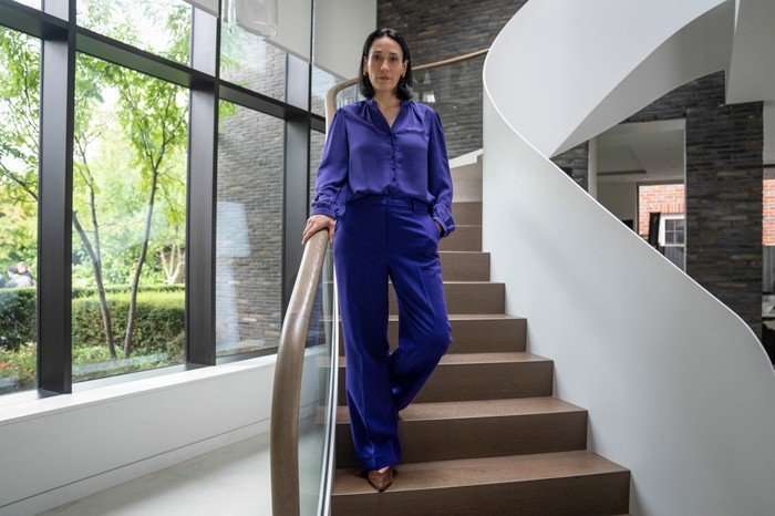 Sian Clifford as Joanne Kemper in Ludwig, wearing a purple outfit and walking down a set of stairs.