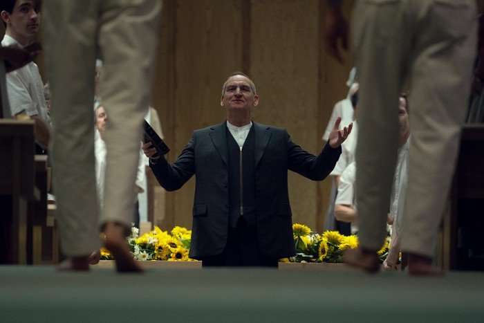 Christopher Eccleston in Unchosen, preaching with his arms outstretched.