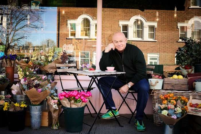 Ross Kemp sat outside a cafe and leaning on the table.