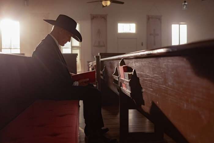 Everett, played by Ed Harris, is older man in a cowboy hat. He's sitting in an empty church, his head bowed in prayer. He's wearing a cowboy hat