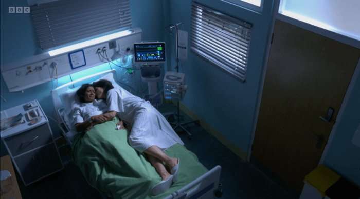 Suki and Eve lie beside each other in a hospital bed in EastEnders.