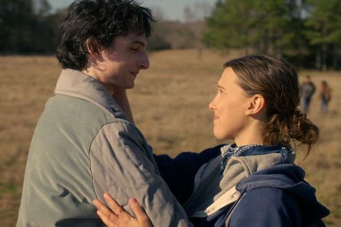 Finn Wolfhard as Mike Wheeler and Millie Bobby Brown as Eleven in Stranger Things season 5, holding each other and smiling at each other