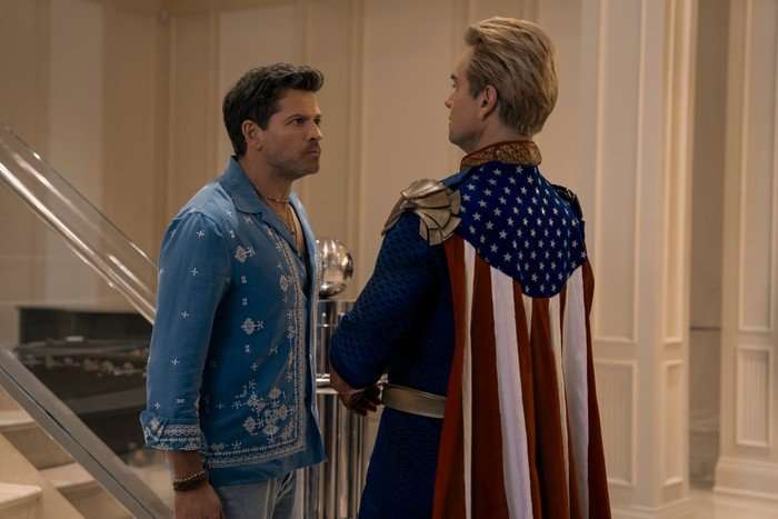 Misha Collins as Malchemical and Antony Starr as Homelander in The Boys. They are stood in a room facing off with one another.