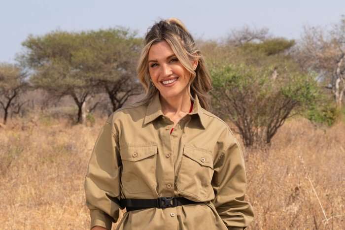 A woman smiling ahead in a safari landscape.