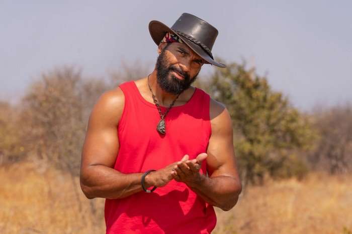 A man looking ahead in a safari landscape rubbing his hands together.
