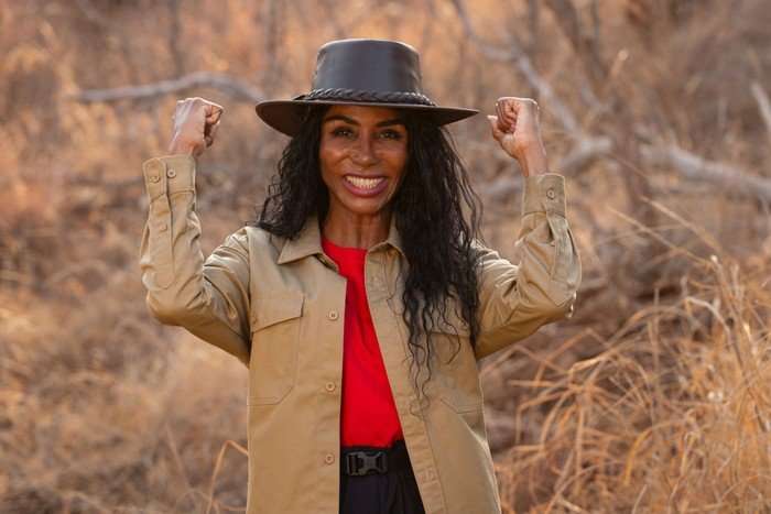 A woman smiling ahead with her clenched fists raised in a victory pose.