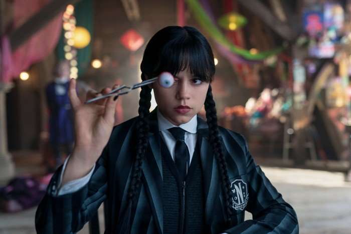 Jenna Ortega as Wednesday Addams in Wednesday season 2, holding forceps with an eye connected to them.