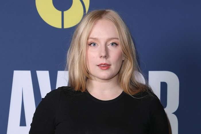 Alexa Davies photographed at a screening, wearing a black top and looking directly at the camera lens