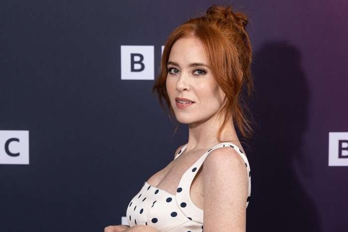 Angela Scanlon posing with her body turned to one side, wearing a white polka dot dress.