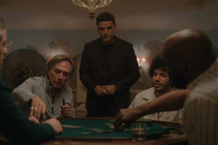 Troy and Benny play poker, while Josh stands between them observing