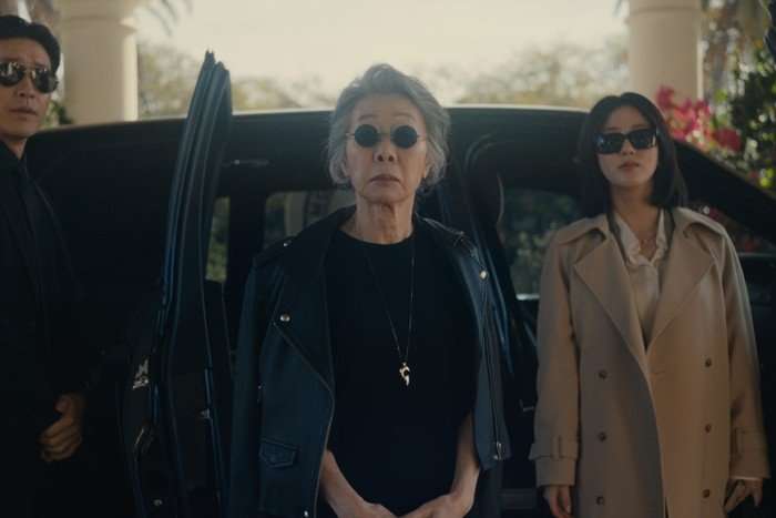 Youn Yuh-jung plays Chairwoman Park in Beef season 2; she is exiting an SUV, wearing sunglasses with a stern expression on her face