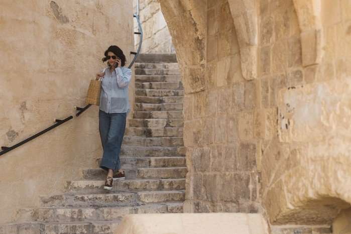 Gemma Arterton as Kate in Secret Service, walking down a set of stone steps while speaking on the phone.